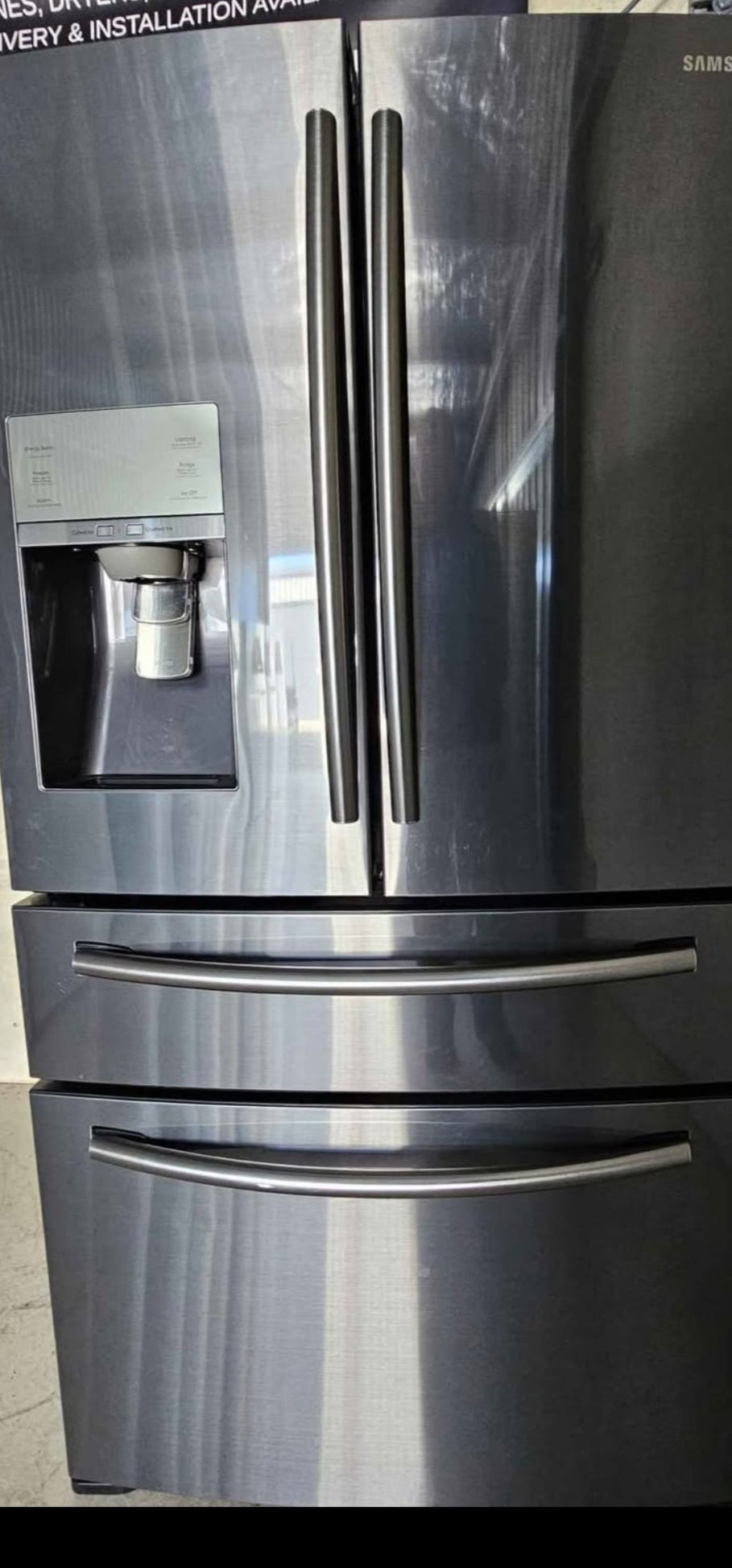 Stainless steel refrigerator with water and ice dispenser on a tiled floor.